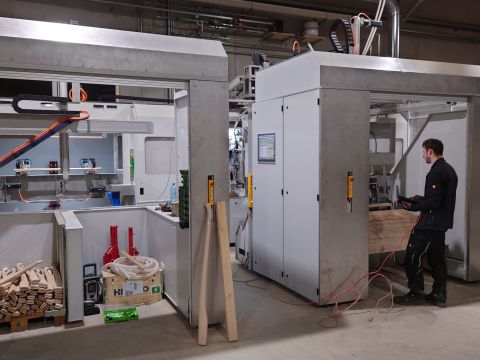 Eine Fertigungslinie einer Holzindustrie-Firma mit einem Mitarbeiter davor